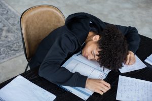 Boy falls asleep while studying. Rests head on his books